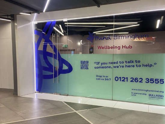 Image of the outside of the mental health hub for Mind Birmingham. Glass windows and blue branding on the outside.